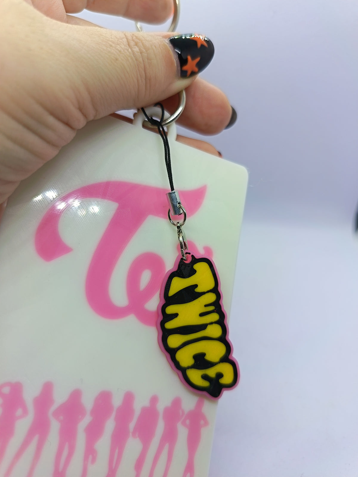 Holder para photocard TWICE, detalle del charm de letras TWICE amarillo y negro.
