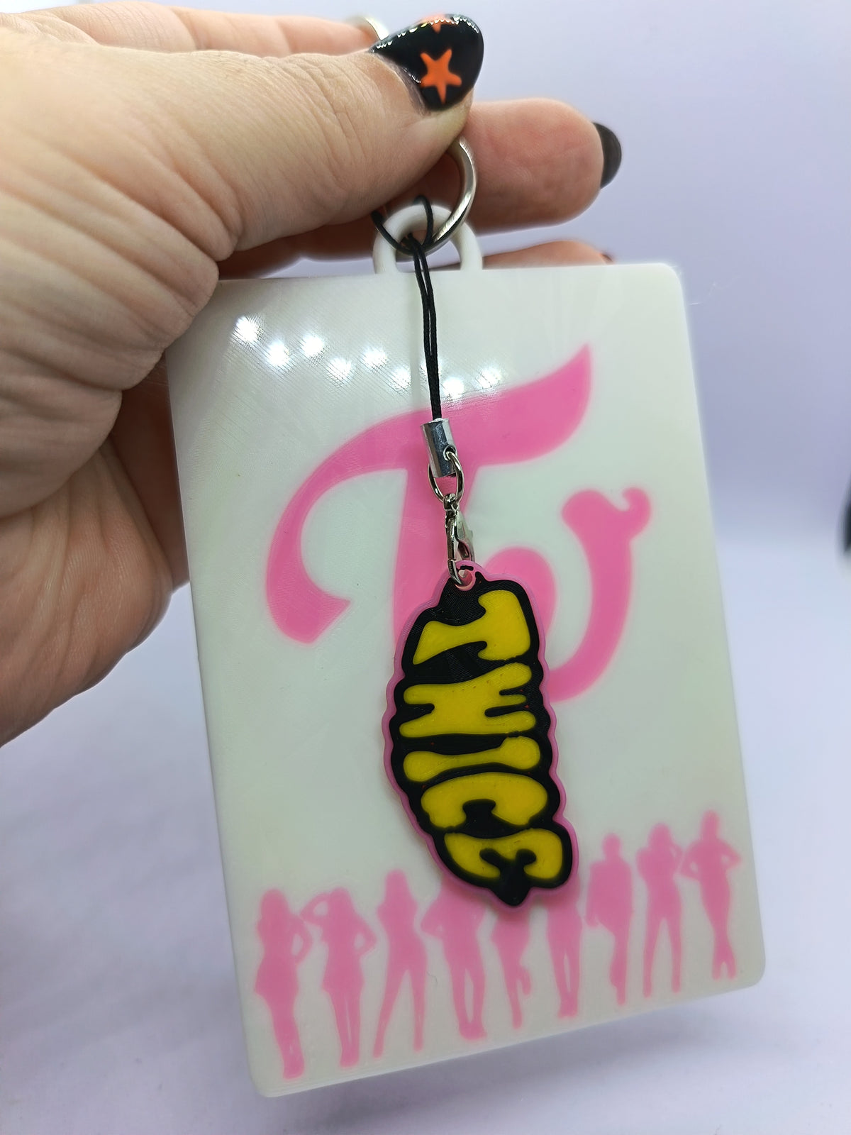 Holder para photocard TWICE, detalle del charm de letras TWICE amarillo y negro.