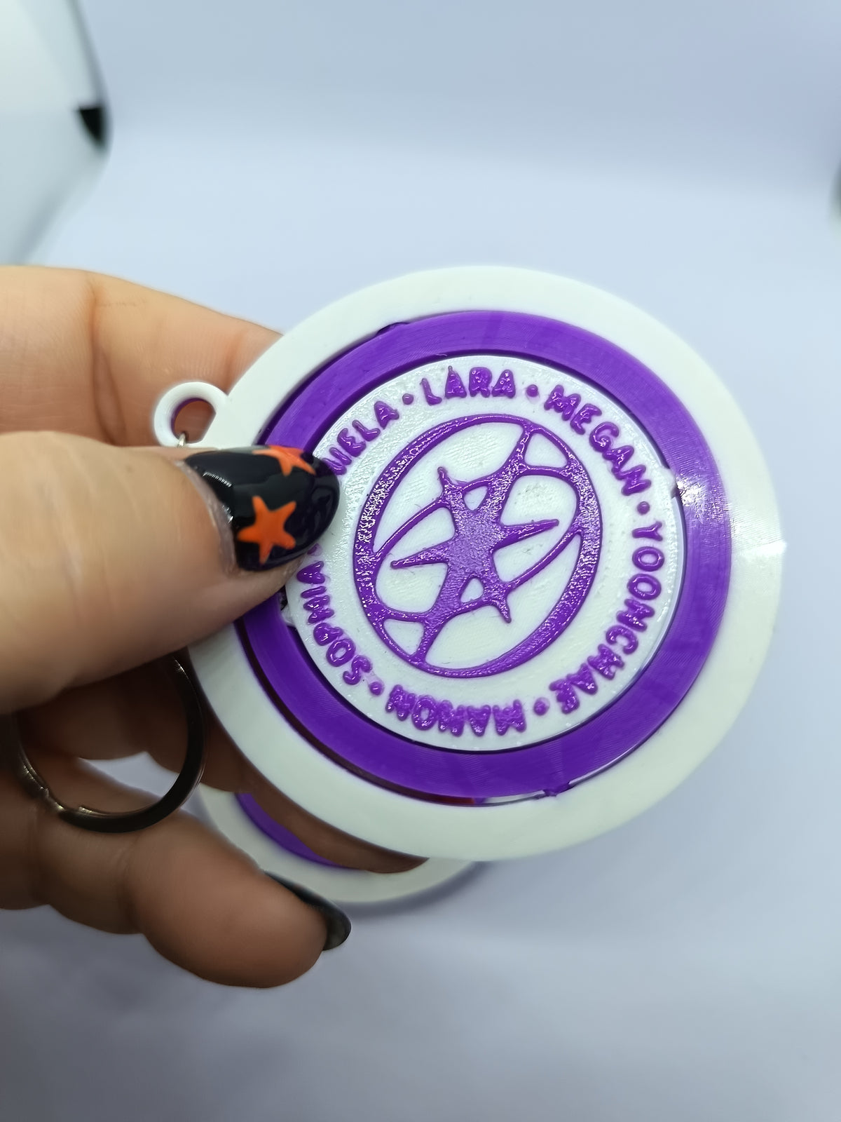Llavero KATSEYE con logo giratorio morado, fotografía 3 del producto.