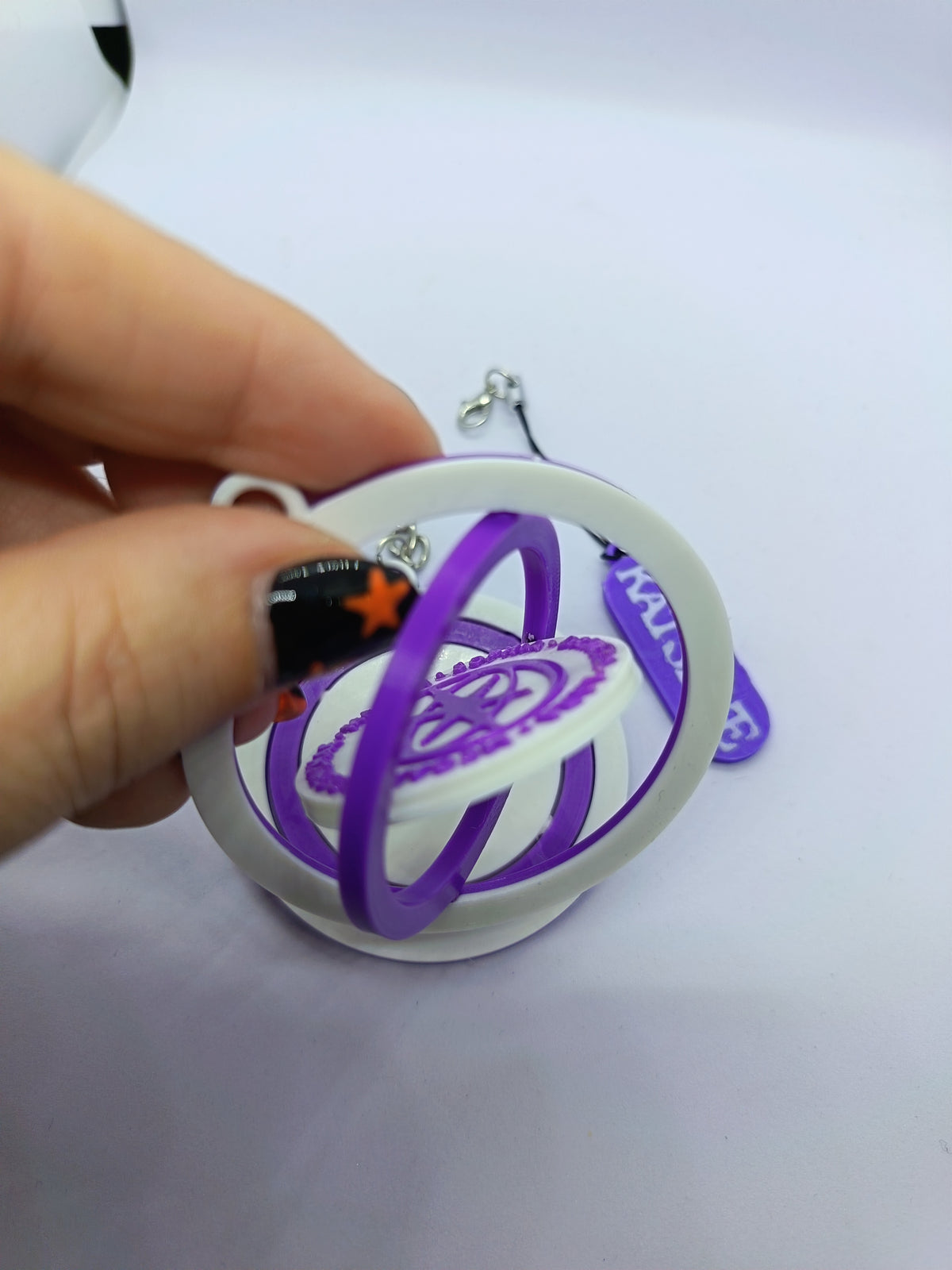 Llavero KATSEYE con logo giratorio morado, fotografía 4 del producto.